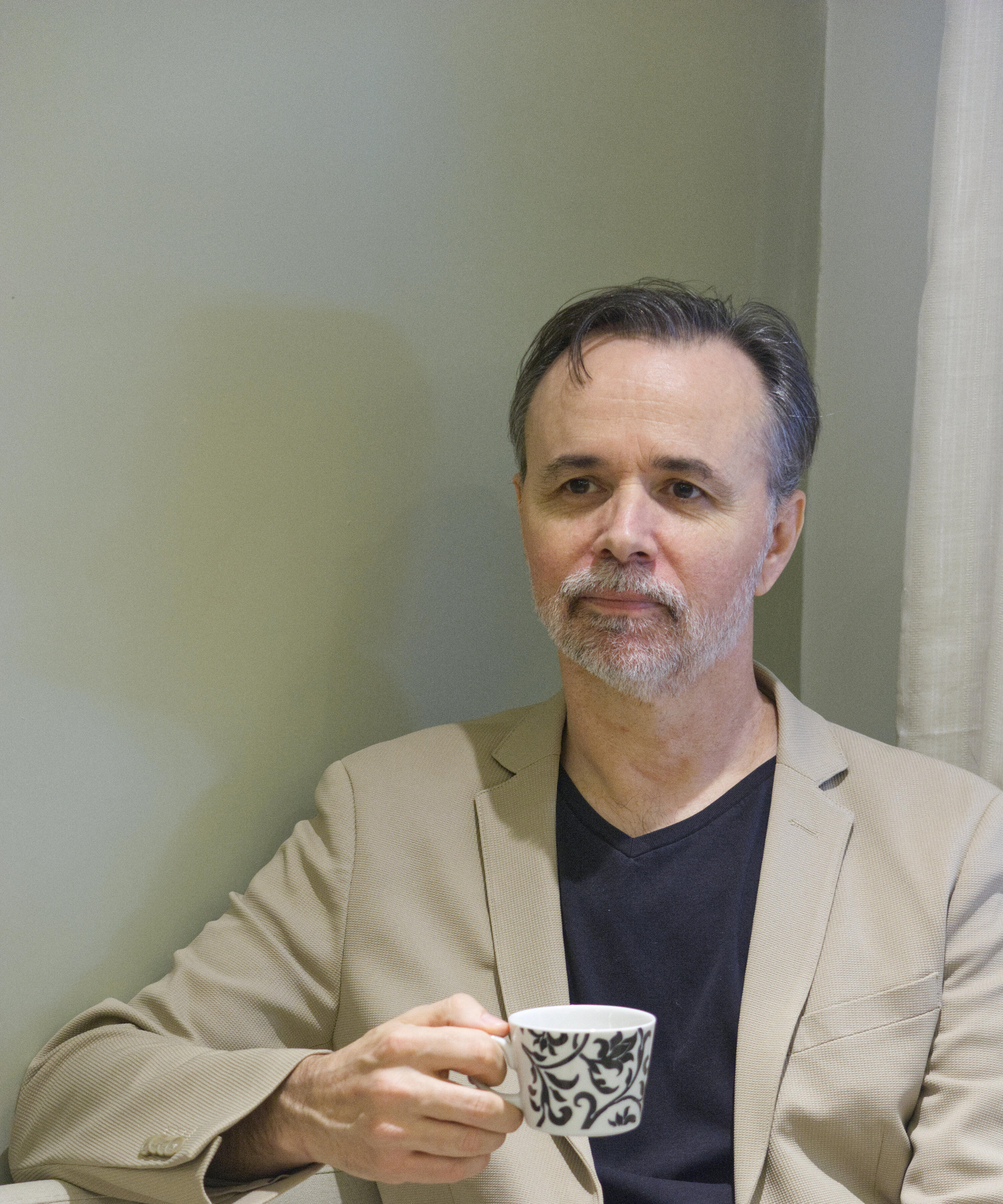 Executive English Coaching & Mentoring Dennis Warren holding a teacup during an individual English mentoring session.